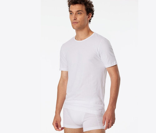 Un homme portant 2 t-shirts SCHIESSER en coton bio, blanc.