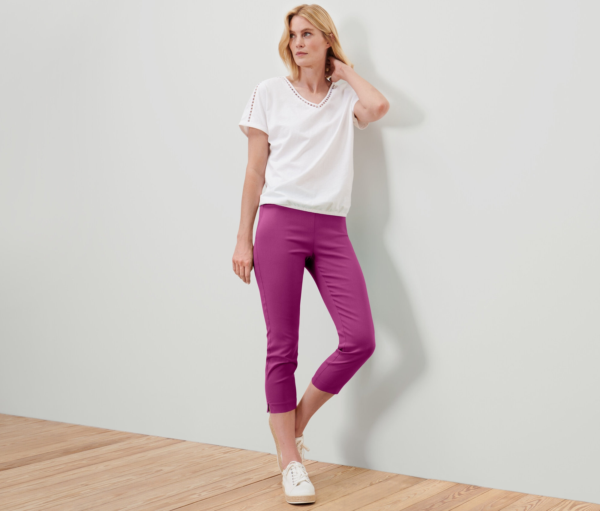 Femme posant en pantalon stretch 7/8 baies, t-shirt blanc et baskets.