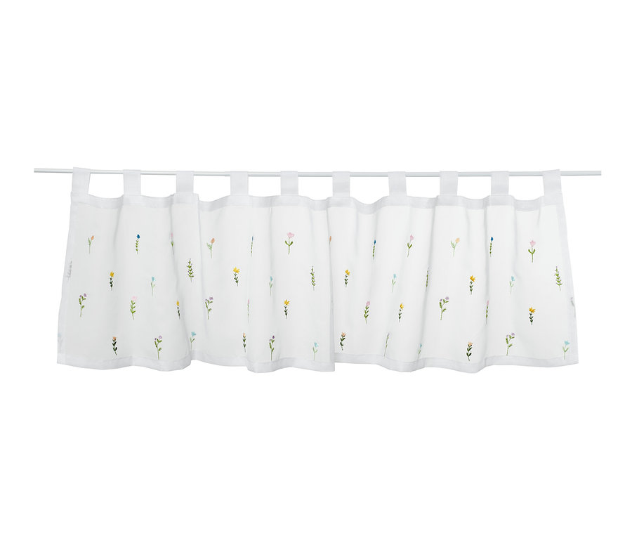 Un rideau de bistrot brodé avec un motif floral suspendu à une tringle à rideau.