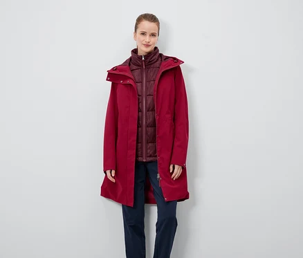 Une femme porte un manteau rouge et un gilet bordeaux.