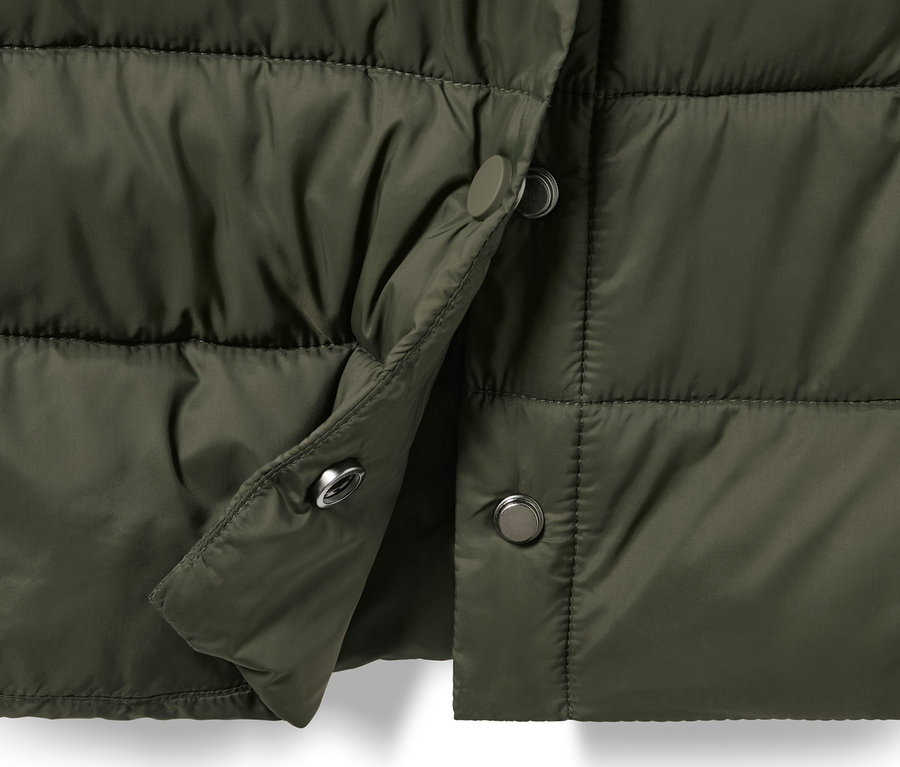 Détail d'un manteau matelassé vert olive avec capuche et boutons-pression.