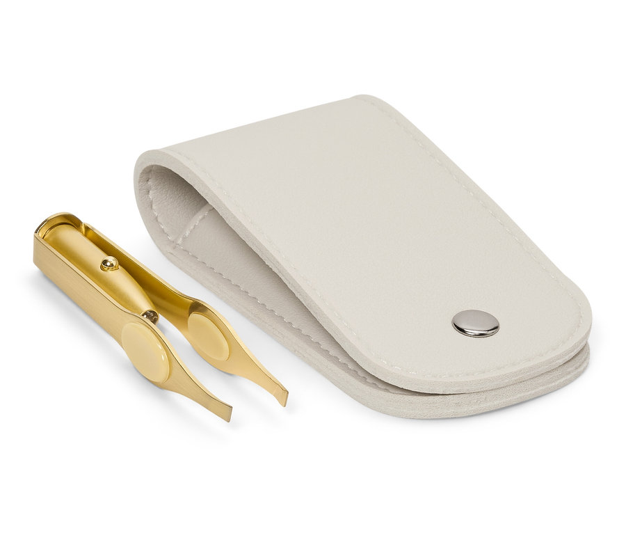 Une pince à épiler dorée repose à côté d'un étui blanc ouvert.