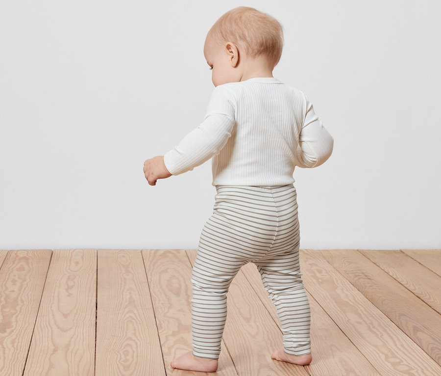 Un bébé marche sur un plancher en bois et porte un legging enfant rayé (lot de 5).