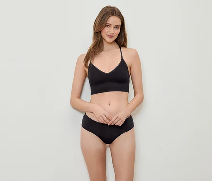 Une femme pose en soutien-gorge de sport et culotte noirs.