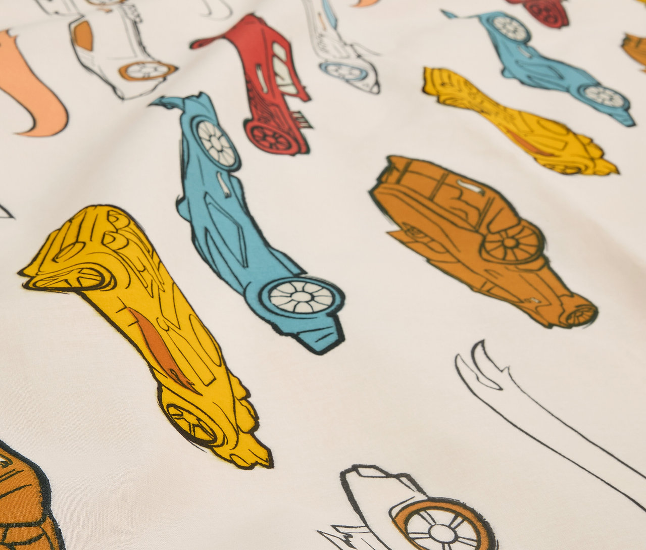 Gros plan sur un tissu imprimé avec des voitures de course stylisées de différentes couleurs.