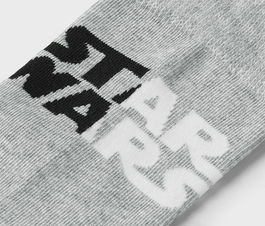 Gros plan d'une chaussette grise avec une inscription noire et blanche.