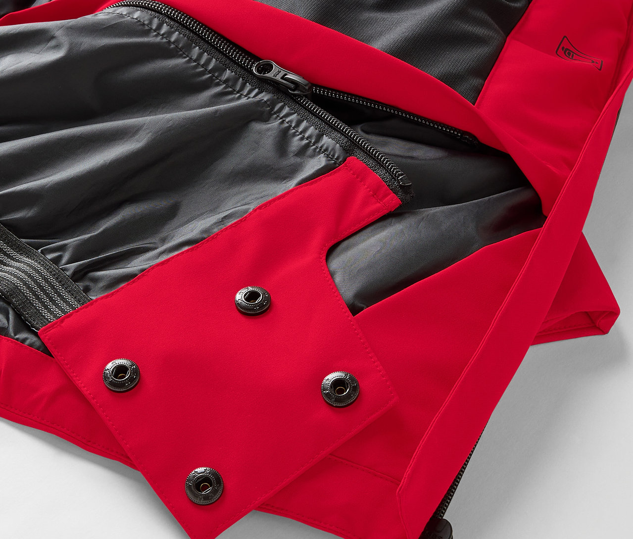 Gros plan d'une veste rouge avec une doublure noire et des boutons-pression.