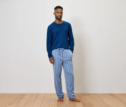 Un homme portant un pyjama bleu à manches longues et un pantalon rayé.