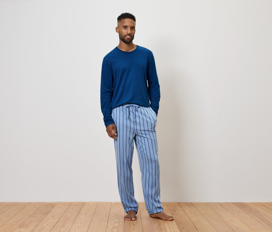 Un homme portant un pyjama bleu à manches longues et un pantalon rayé.