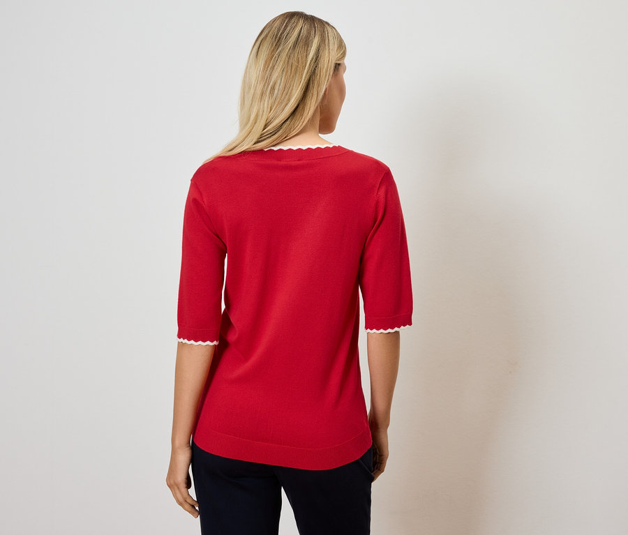 Femme portant un pull rouge à manches trois quarts avec bordure blanche.