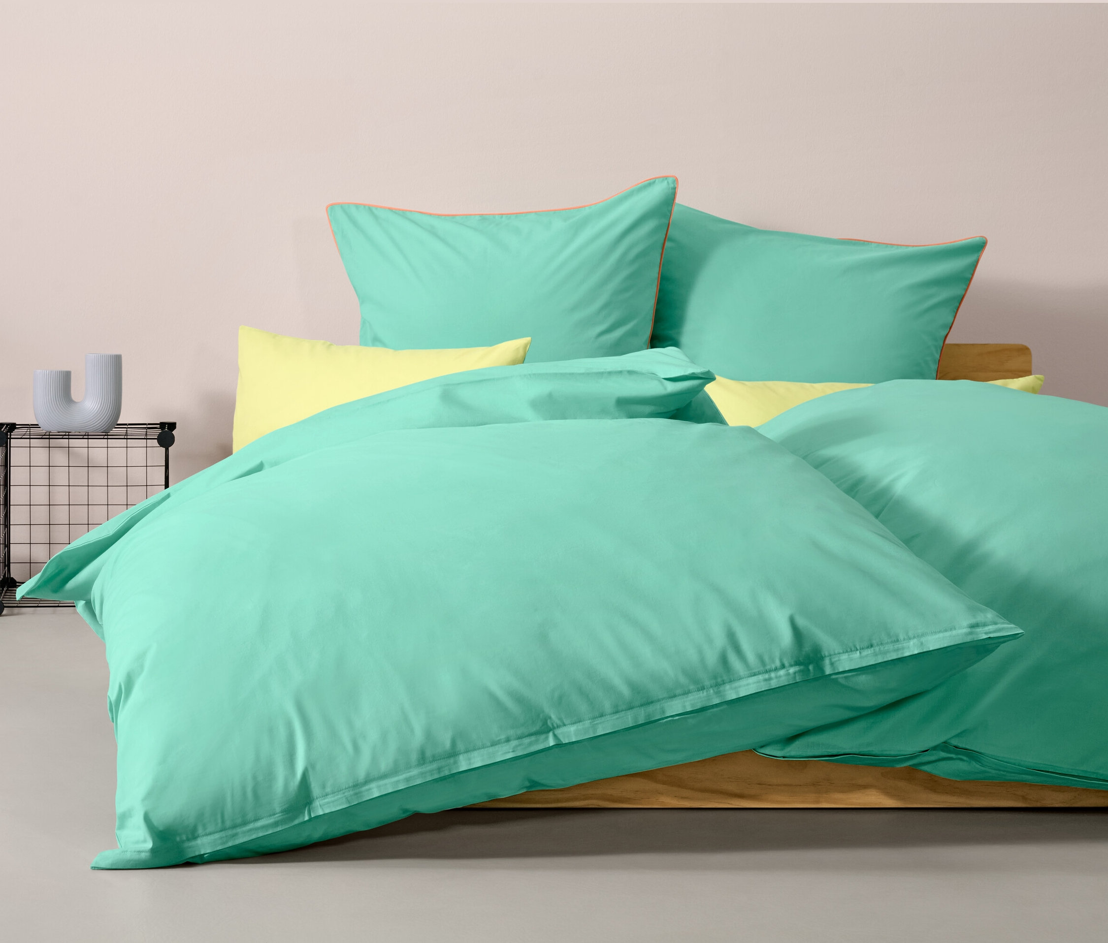 Parure de lit en renforcé turquoise taille normale sur un lit avec des oreillers jaunes.