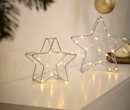 Deux étoiles en fil de fer argentées avec de petites lumières sont posées sur une surface blanche.