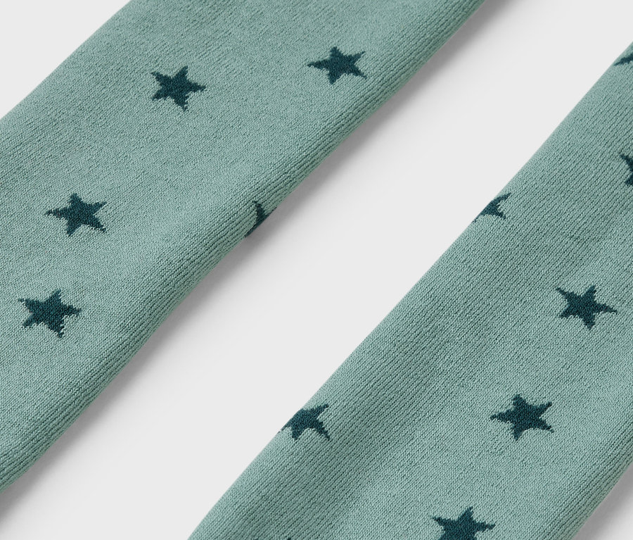 Détail de deux collants thermiques pour enfants bleu-vert avec des étoiles.