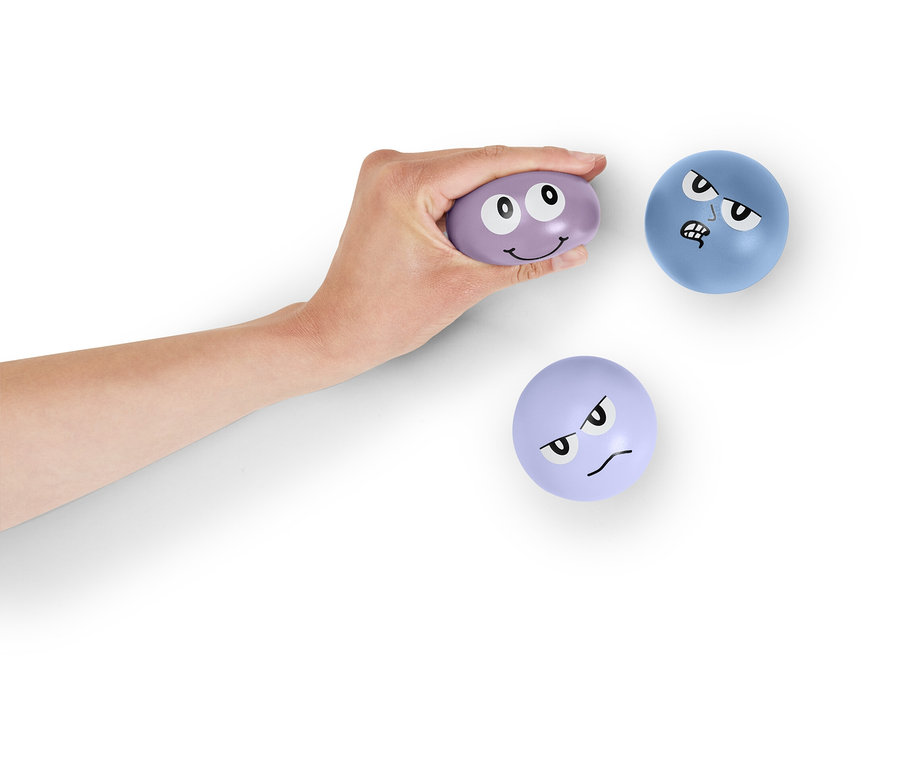 Une main tient une balle violette avec un visage. Deux autres balles avec un visage sont posées sur un fond blanc.