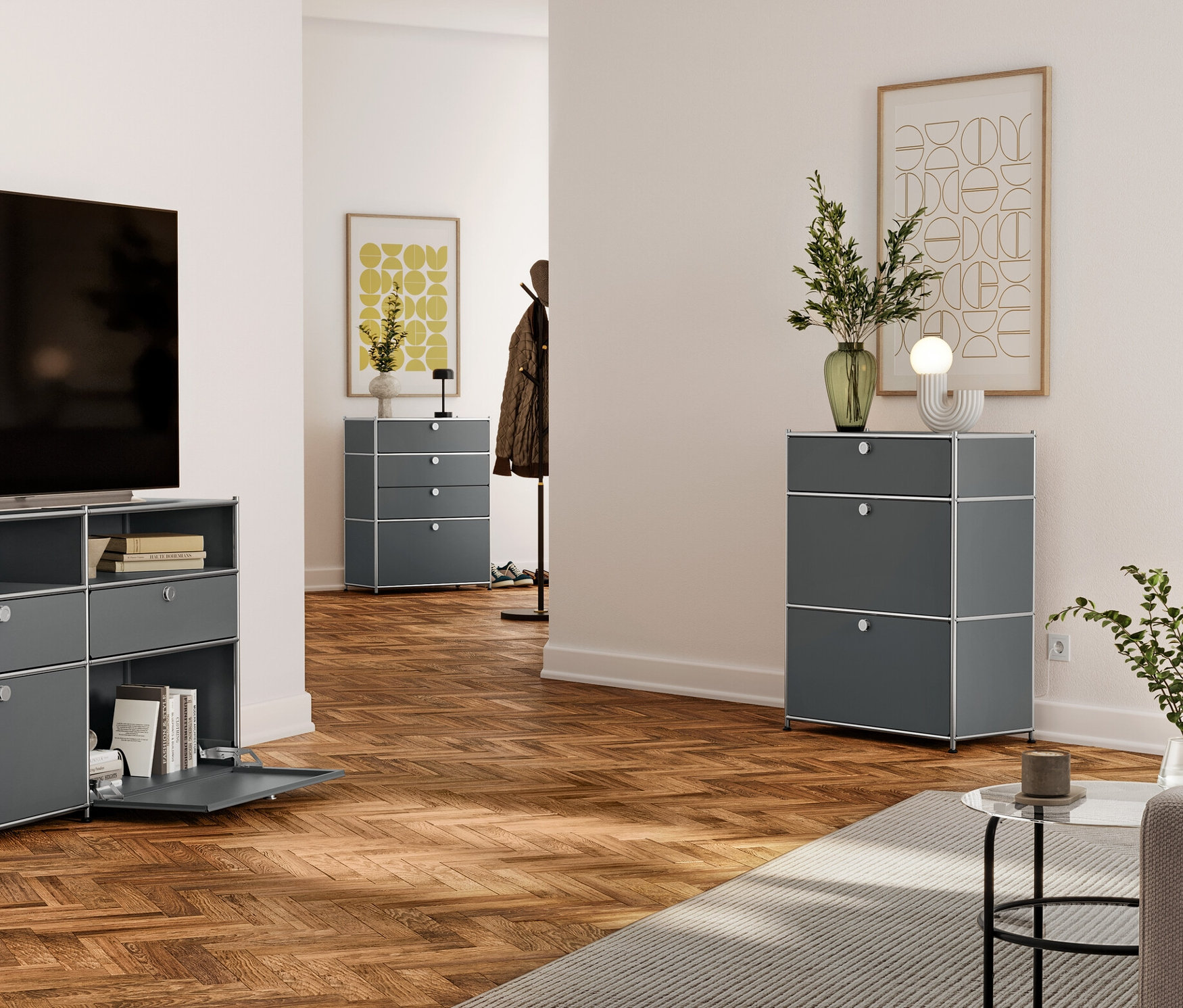 Salon avec TV sur une commode en métal gris avec tiroirs et étagères ouvertes. À l'arrière-plan, une commode grise à trois tiroirs et une autre dans le couloir.