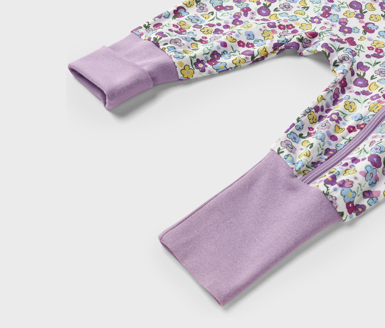 Gros plan d'une combinaison lilas à motif floral, avec fermeture éclair et manches longues.