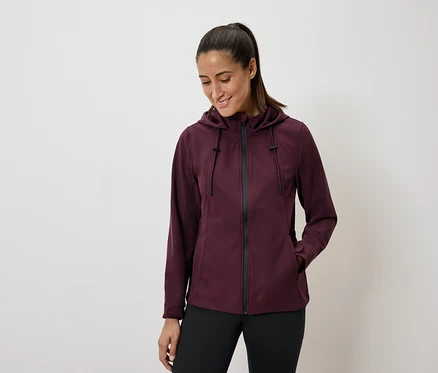 Femme portant une veste à capuche bordeaux et un legging noir.