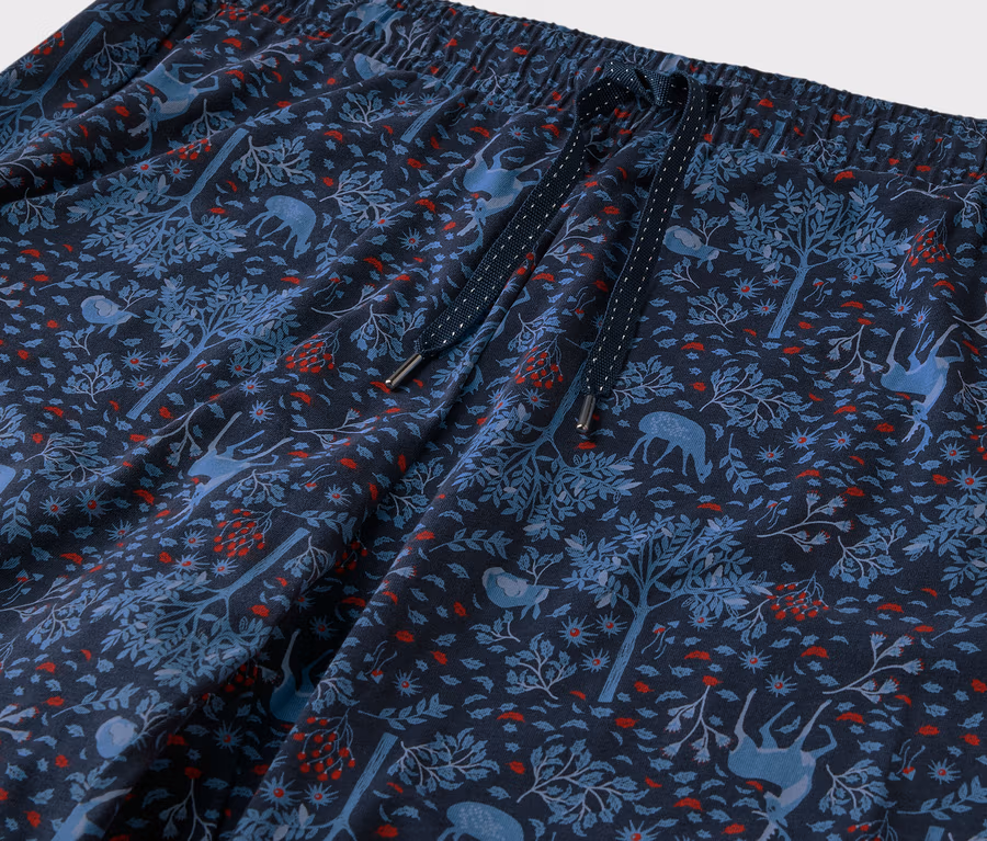 Gros plan d'un pantalon bleu avec un motif de forêt, d'arbres et de cerfs.