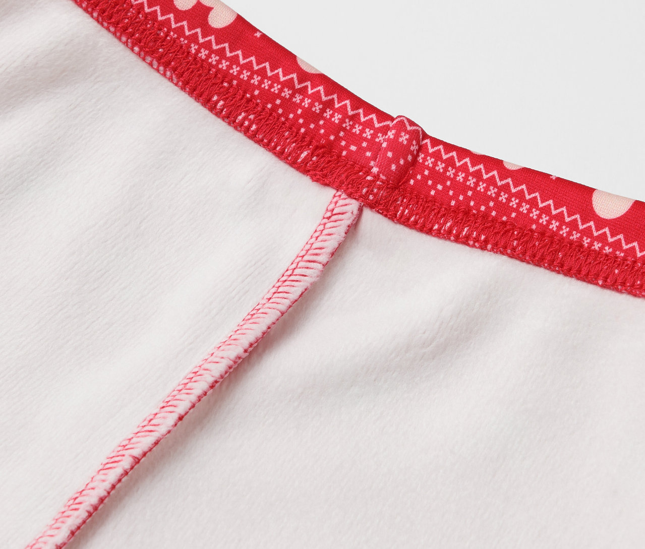 Détail d'un vêtement blanc avec une bordure rouge à pois blancs.