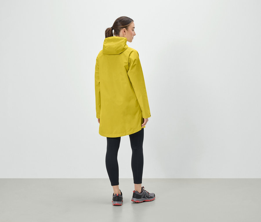 Une femme portant une veste à capuche jaune, un legging noir et des chaussures de sport, vue de dos.