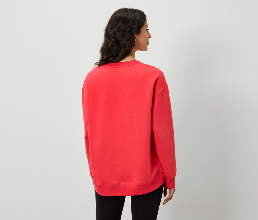 Vue arrière d'une femme portant un sweat-shirt rouge et un pantalon noir.