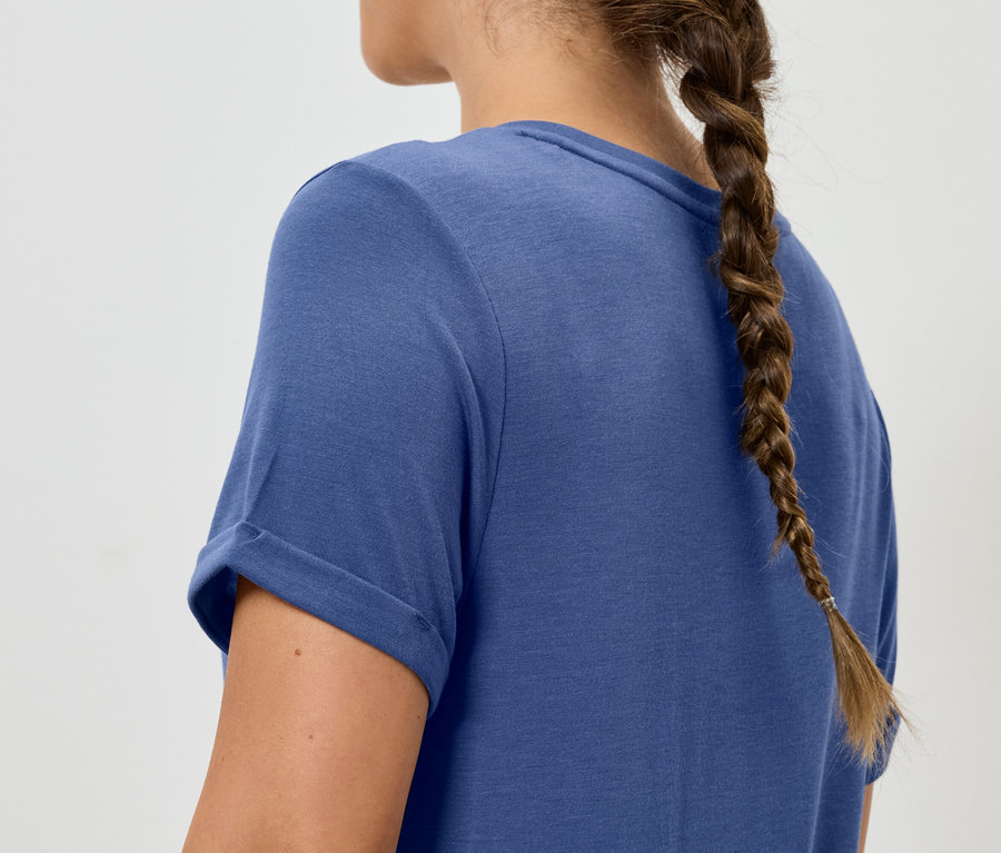 Femme avec une tresse portant un t-shirt bleu.