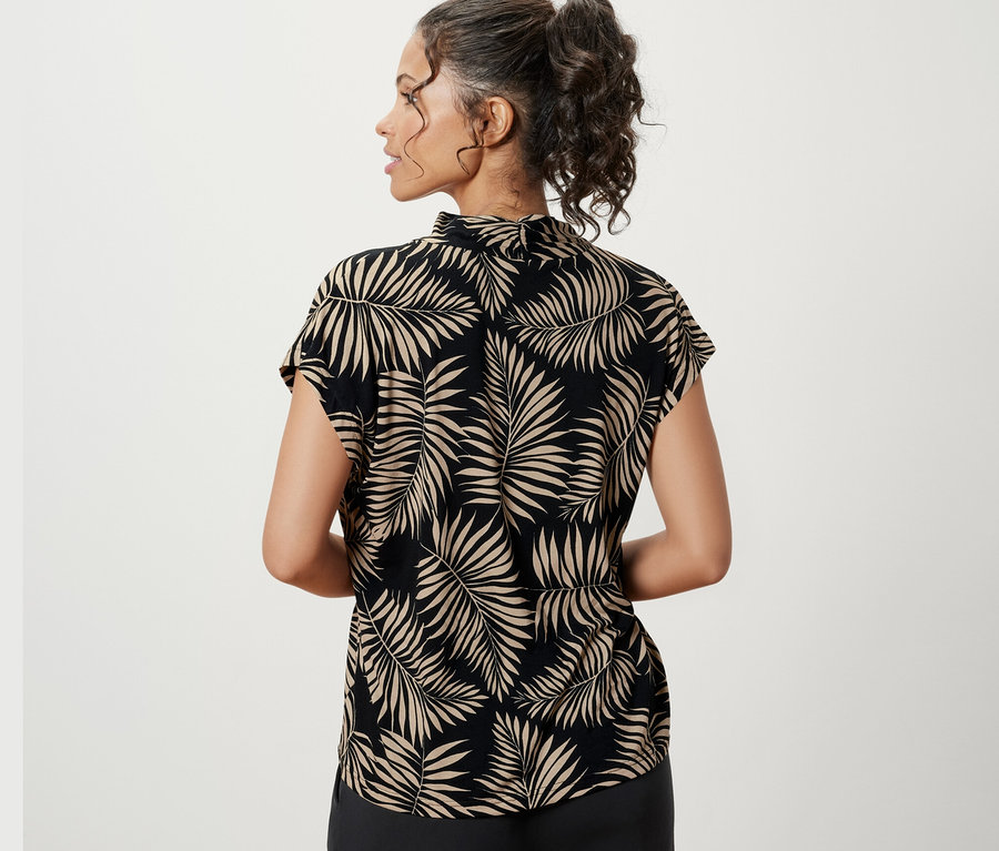 Une femme porte une blouse imprimée avec encolure en V.