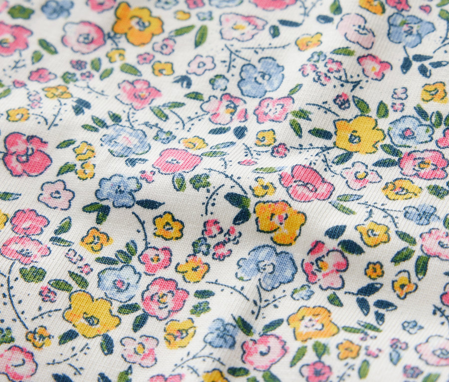 Gros plan sur des leggings pour enfants avec un motif floral dans les tons rose, bleu et jaune.