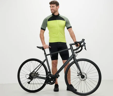 Un homme est debout à côté d'un vélo et porte un maillot de cyclisme jaune.