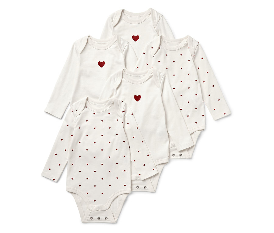 Cinq bodies blancs à manches longues pour bébé, certains avec un cœur rouge au centre, d'autres avec un motif de cœurs rouges.