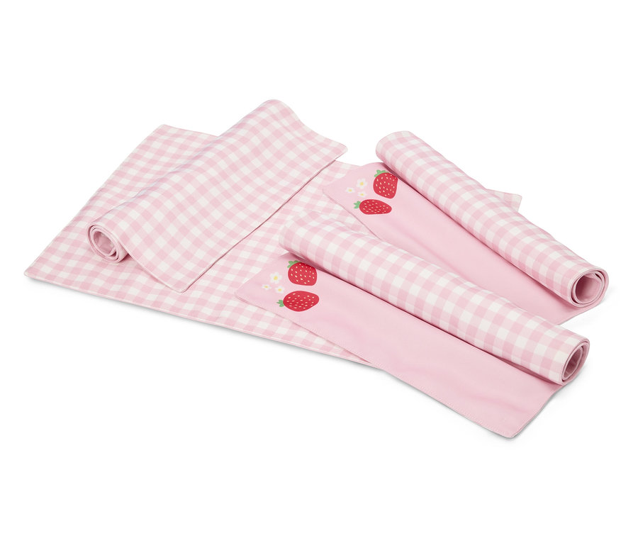 Sur un fond blanc se trouvent une couverture à carreaux rose et blanc et deux tissus roses avec des motifs de fraises, partiellement enroulés.