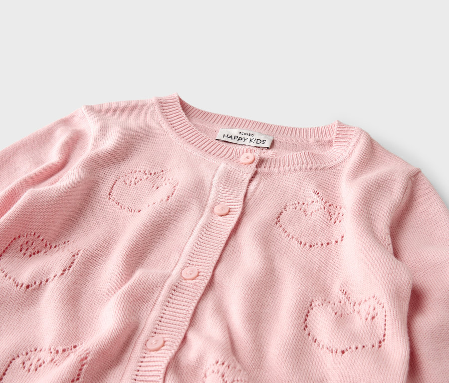 Gros plan sur un cardigan rose avec un motif de pommes.