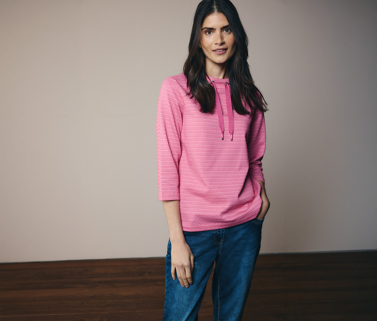 Femme portant un jean et un sweat-shirt CECIL rose à capuche et manches 3/4, une main dans la poche.