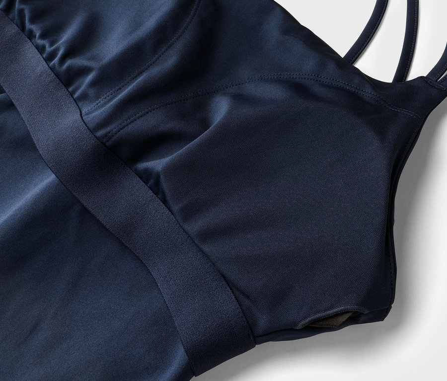 Gros plan d'un haut de sport bleu marine avec bretelles et soutien-gorge intégré sur fond blanc.