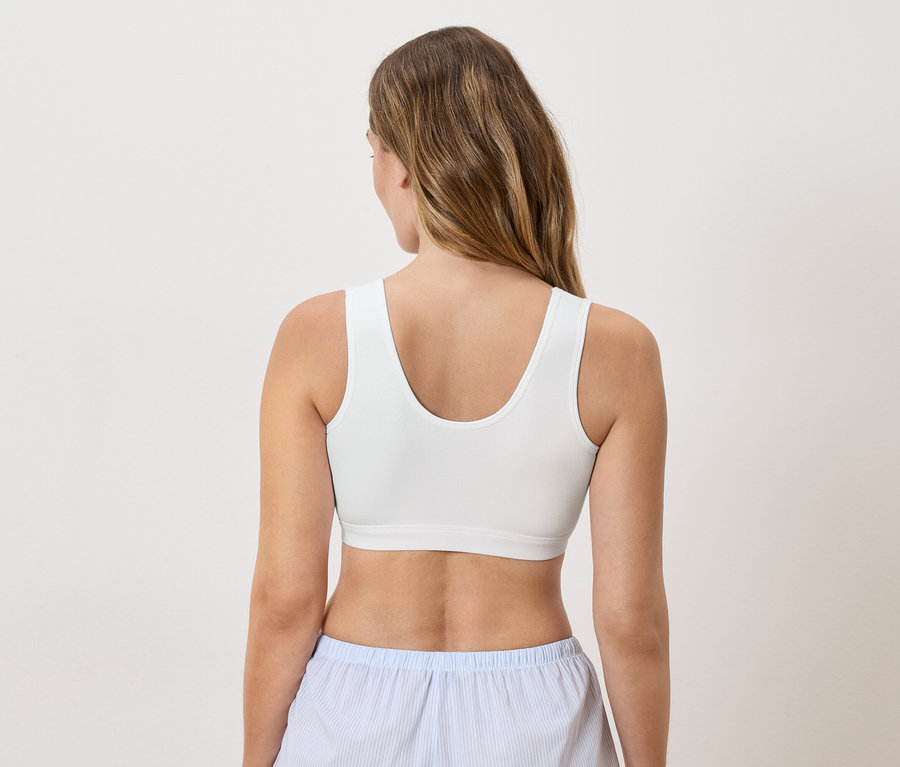 Vue arrière d'une femme blonde portant un soutien-gorge blanc et un pantalon de pyjama rayé bleu et blanc.