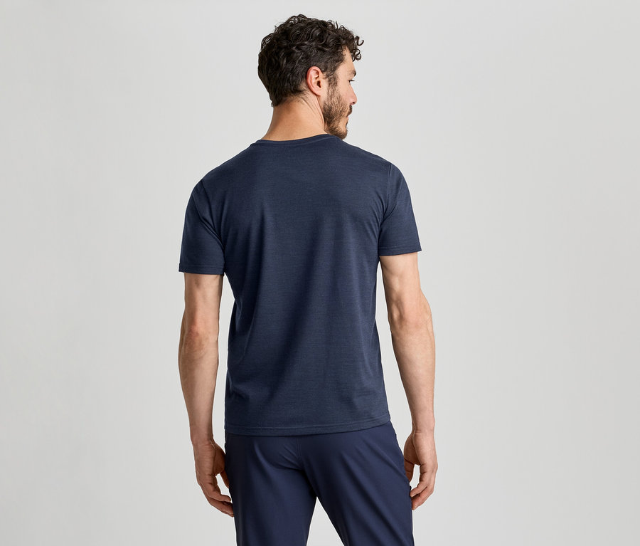 Un homme de dos, portant un t-shirt bleu foncé et un pantalon bleu foncé, regardant vers la droite.