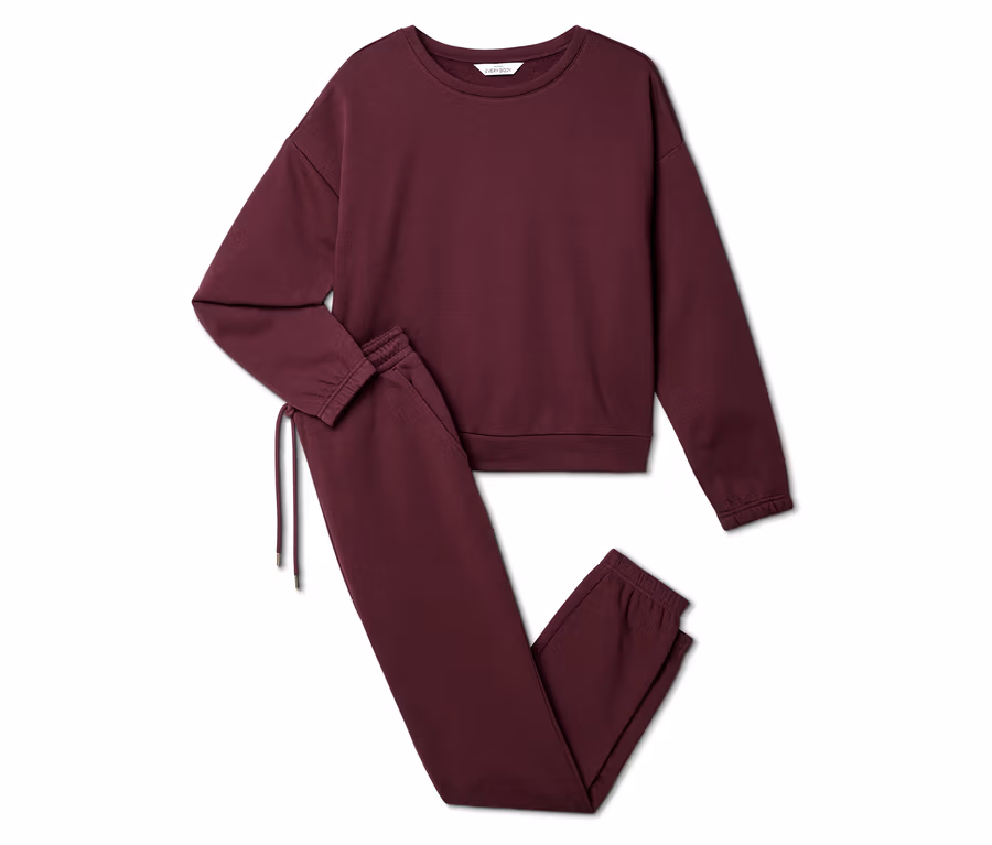 Ensemble de survêtement bordeaux composé d'un sweat-shirt et d'un pantalon de jogging posé sur un fond blanc.