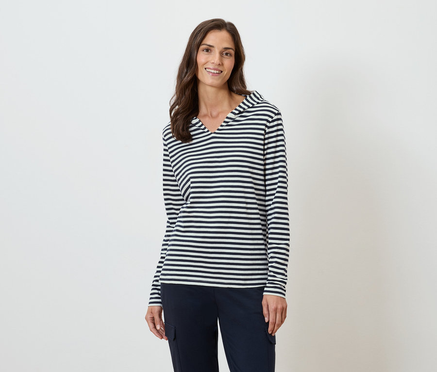 Femme portant un haut rayé à manches longues avec capuche et un pantalon bleu marine.