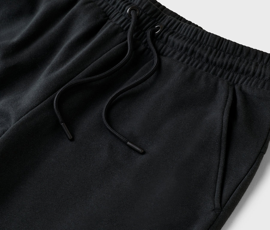 Gros plan d'un pantalon de jogging noir avec cordon de serrage et poches.