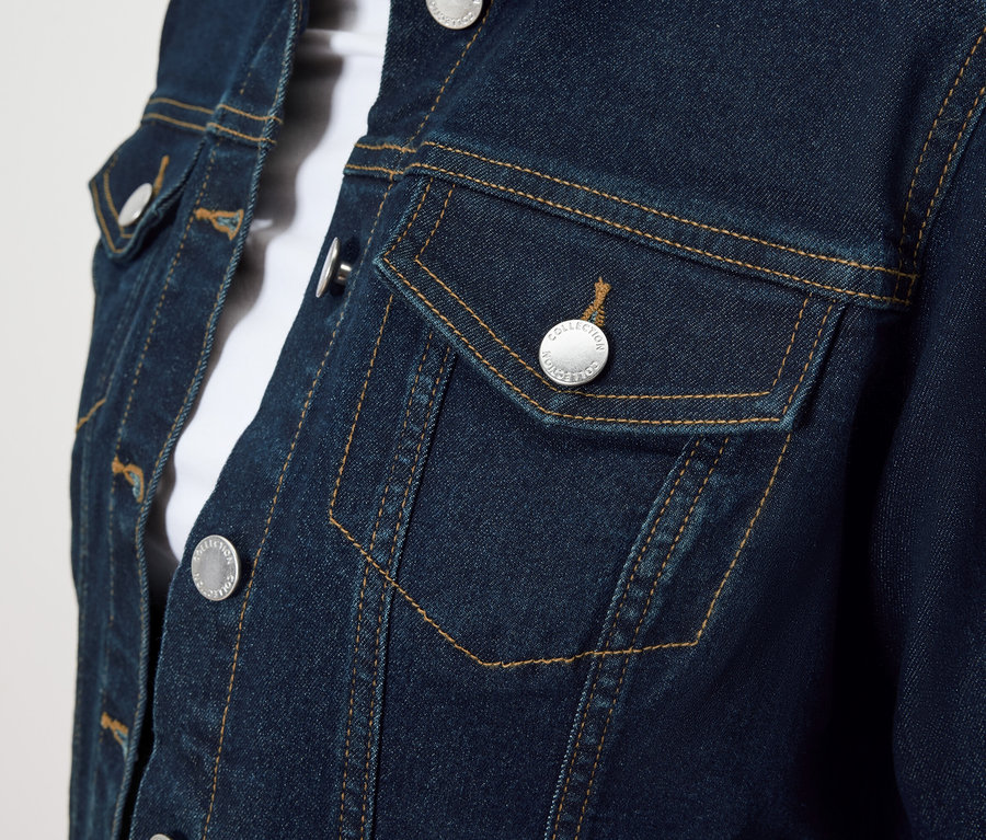 Gros plan sur une veste en jean bleue avec des boutons argentés et une poche poitrine.