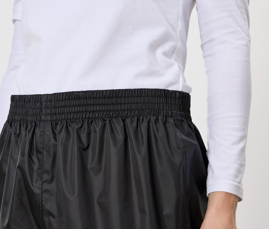 Gros plan d'une personne portant une jupe noire à taille élastique et un haut blanc à manches longues.