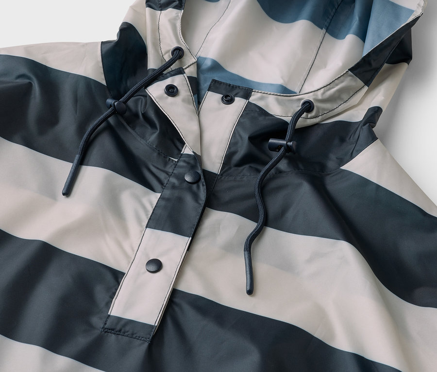 Gros plan sur un imperméable rayé gris et blanc avec capuche et cordon de serrage.