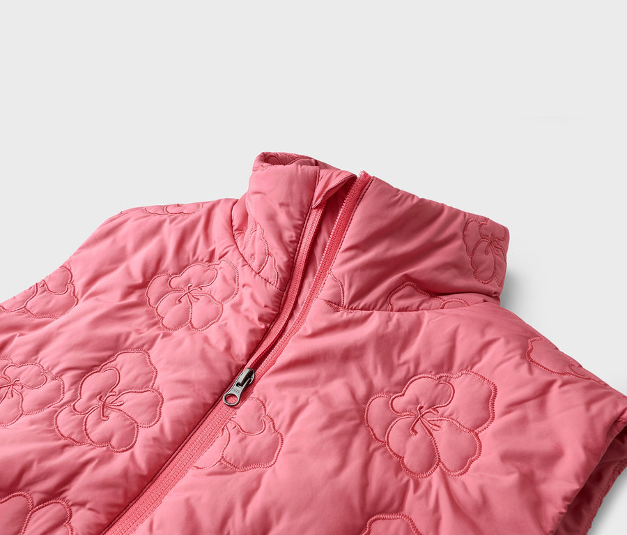 Gros plan d'un gilet rose matelassé avec un motif floral et une fermeture éclair.