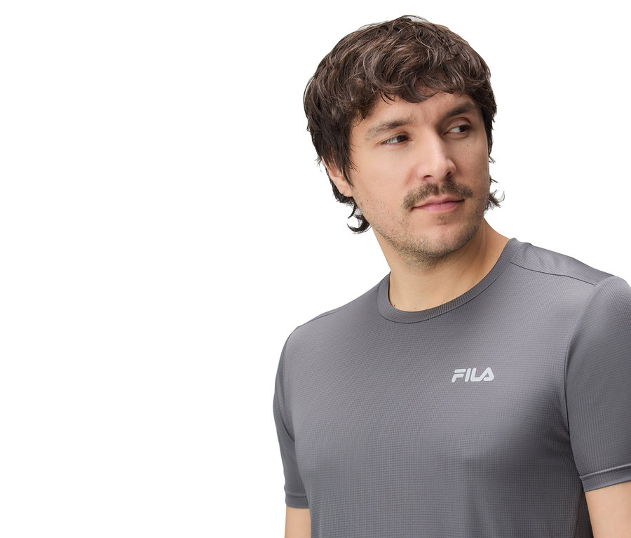 Un homme porte un t-shirt Fila gris.