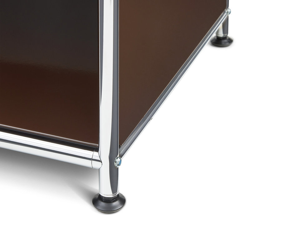 Gros plan du coin inférieur d'un meuble modulaire avec des panneaux marron brillants et des cadres en métal chromé, reposant sur des pieds noirs.