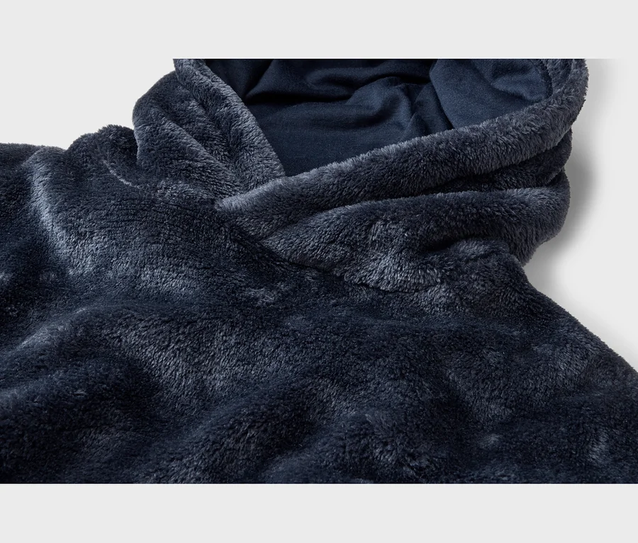 Gros plan sur un sweat à capuche en polaire bleu foncé et moelleux, montrant le matériau texturé et l'ouverture de la capuche.