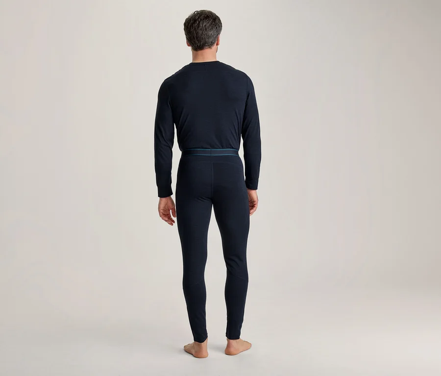 Homme de dos, portant un sous-vêtement thermique à manches longues bleu foncé et un pantalon thermique long avec une fine bande bleue à la taille.