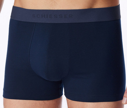 Homme portant un boxer bleu marine avec le logo SCHIESSER sur la ceinture.