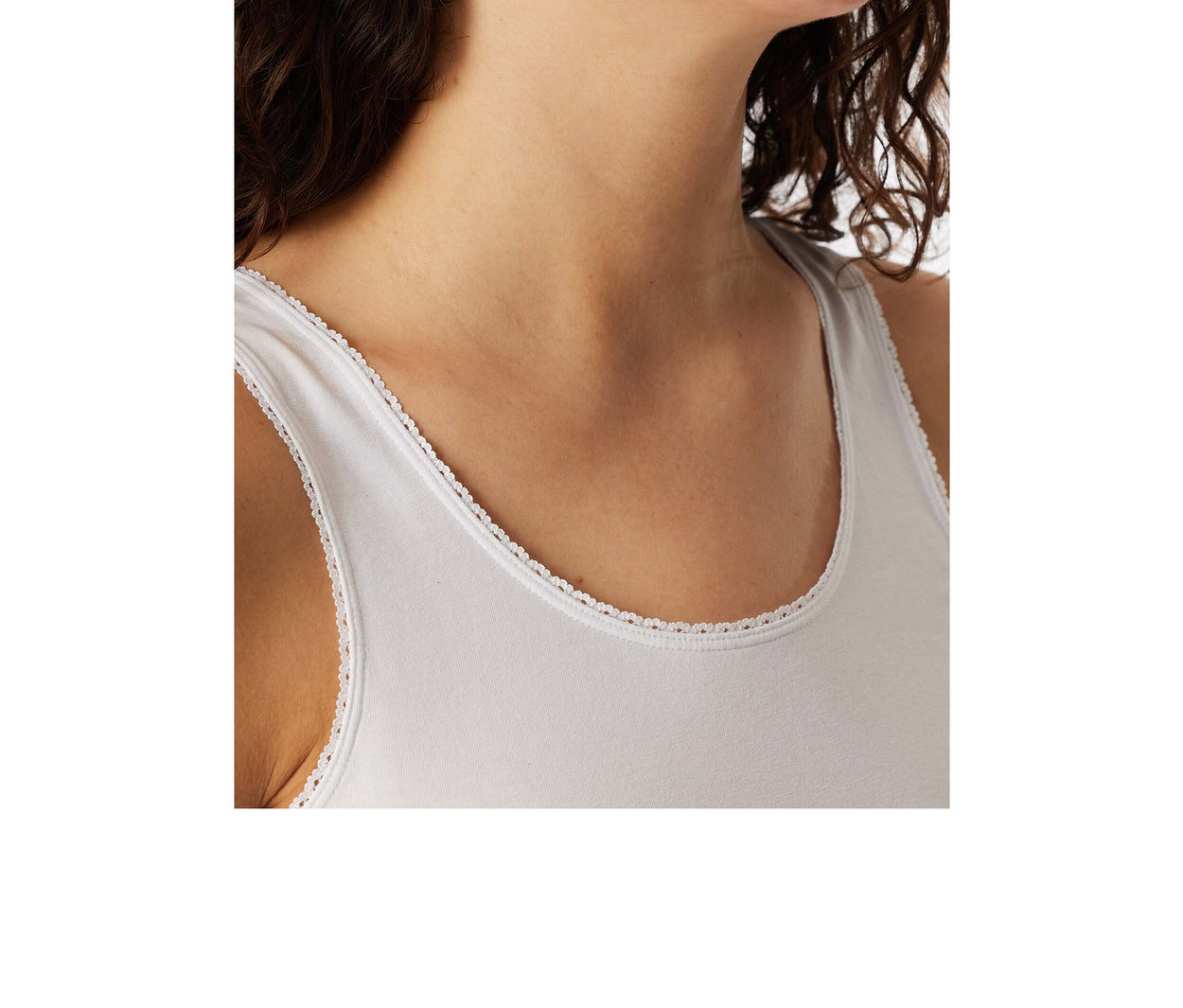 Femme portant un top à bretelles SCHIESSER blanc avec une délicate bordure en dentelle, souriante.