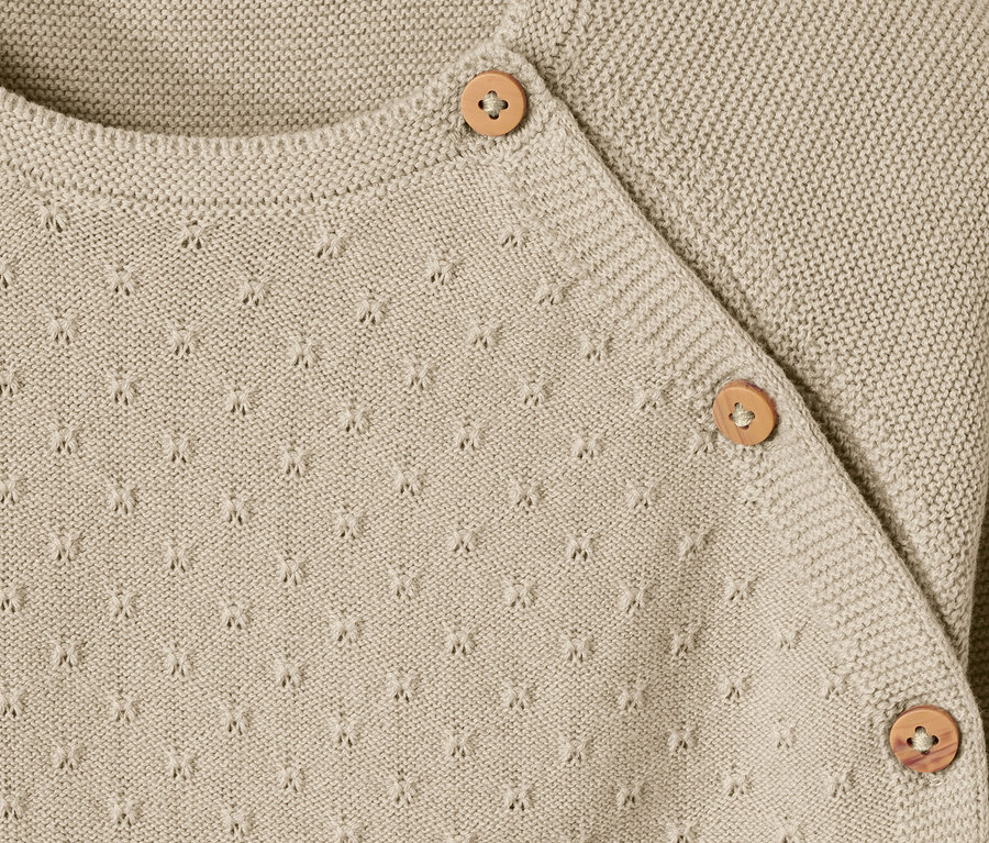 Détail d'une jaquette en maille bébé avec des boutons.
